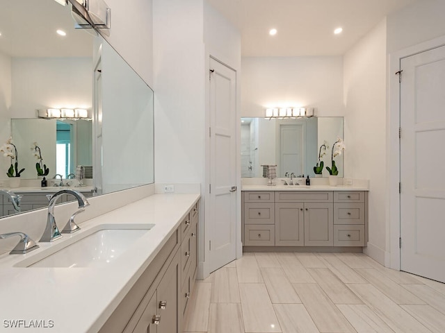 full bath with a sink, two vanities, and recessed lighting