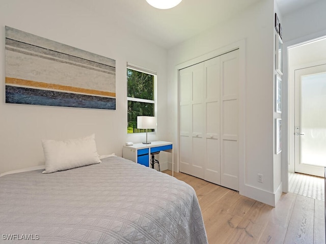 bedroom with light wood-style floors, a closet, and baseboards