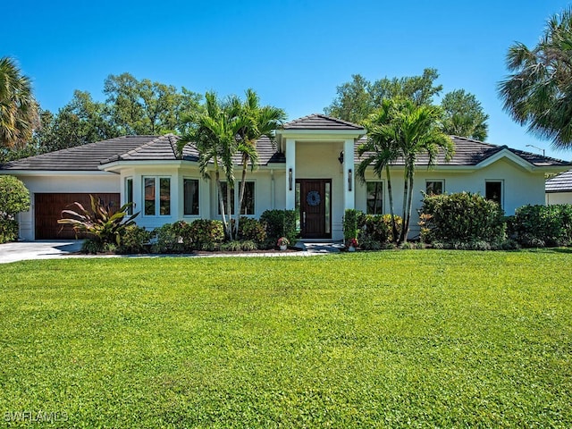 view of front of house with a front yard, driveway, stucco siding, a garage, and a tile roof