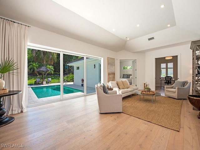 living room featuring visible vents, light wood-style flooring, recessed lighting, and vaulted ceiling