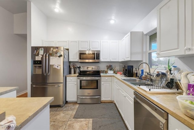 kitchen with a sink, white cabinetry, appliances with stainless steel finishes, light countertops, and lofted ceiling