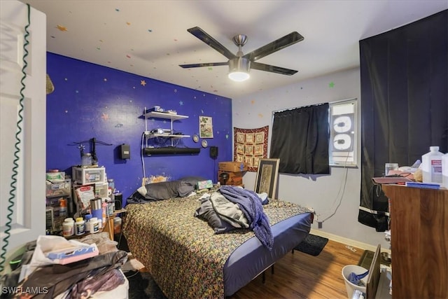 bedroom featuring ceiling fan, baseboards, and wood finished floors