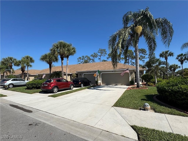 ranch-style home featuring concrete driveway, an attached garage, a front lawn, and stucco siding