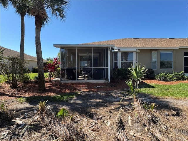 back of property featuring stucco siding, roof with shingles, and a sunroom