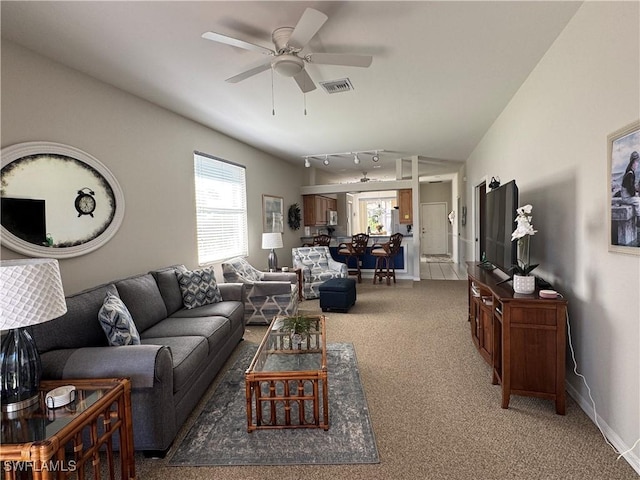 living room featuring a ceiling fan, visible vents, a wealth of natural light, and light carpet