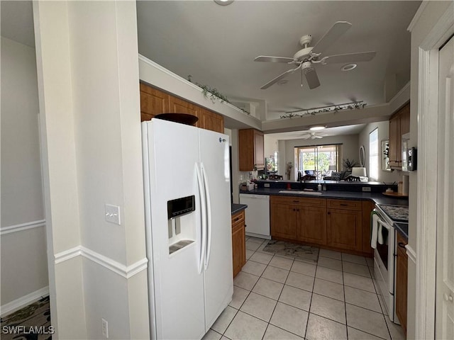 kitchen with white appliances, light tile patterned floors, a ceiling fan, dark countertops, and brown cabinets