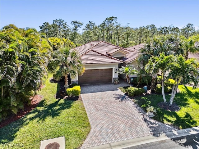 13117 Cardeto Ct, Estero, FL 33928 - view of front of property featuring a front yard, stucco siding, a garage, a tile roof, and decorative driveway