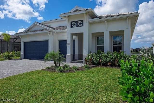 prairie-style home with a tile roof, a front lawn, decorative driveway, and a garage