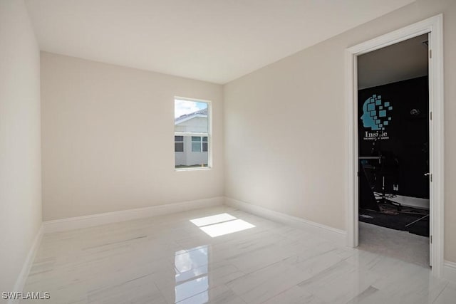 unfurnished room featuring baseboards and marble finish floor