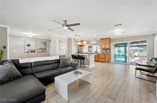 living room featuring visible vents, light wood-style flooring, crown molding, and a ceiling fan