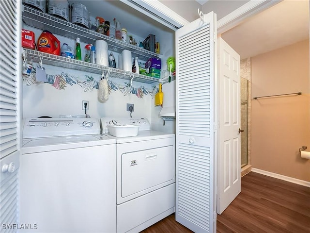 washroom featuring washer and dryer, laundry area, dark wood-style floors, and baseboards