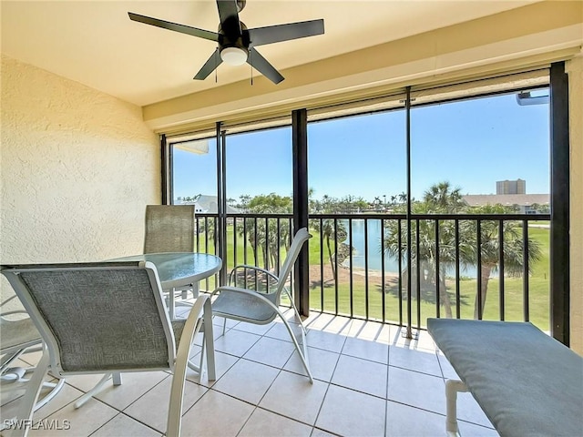 sunroom featuring a water view and ceiling fan