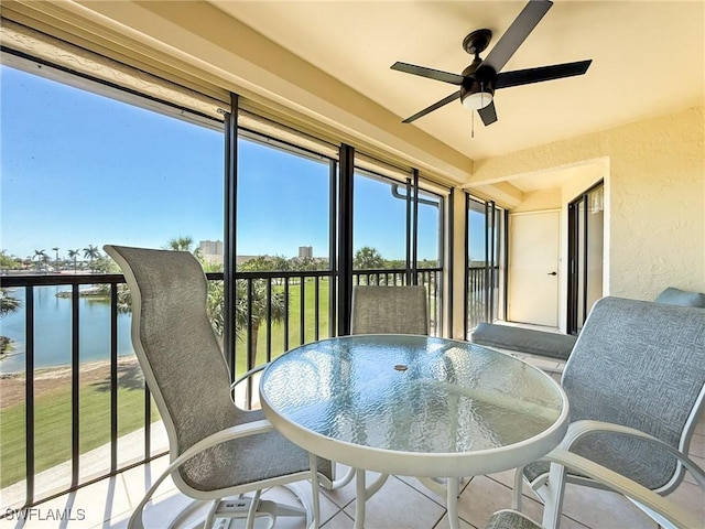 sunroom with a healthy amount of sunlight, ceiling fan, and a water view