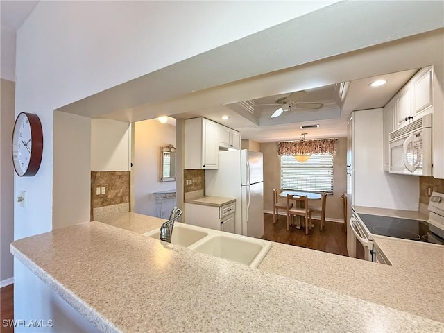 kitchen featuring a sink, a tray ceiling, recessed lighting, white appliances, and ceiling fan