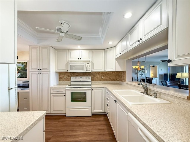 kitchen featuring crown molding, ceiling fan with notable chandelier, white appliances, a raised ceiling, and a sink