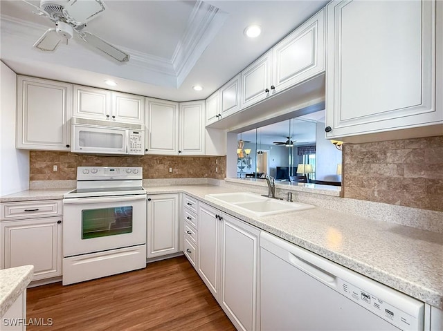 kitchen featuring white appliances, a tray ceiling, ceiling fan, a sink, and crown molding