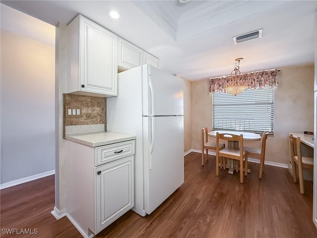 kitchen with visible vents, dark wood finished floors, freestanding refrigerator, light countertops, and decorative backsplash