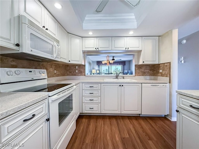 kitchen with dark wood-style floors, white appliances, white cabinetry, a raised ceiling, and a sink