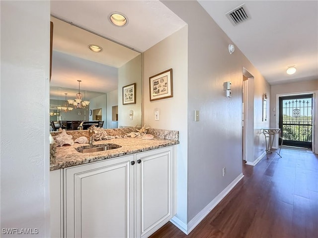 interior space with baseboards, dark wood-style floors, visible vents, and a sink