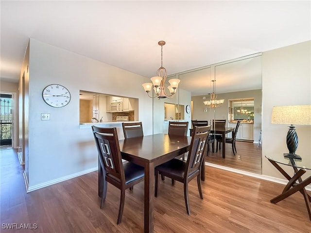 dining space with a notable chandelier, baseboards, and wood finished floors