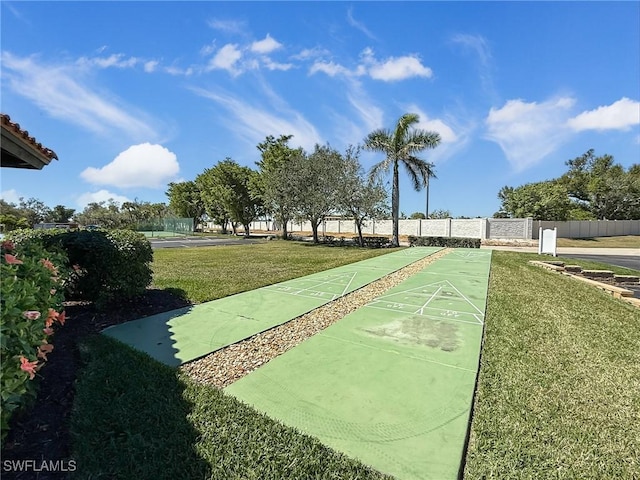 surrounding community with shuffleboard, a lawn, and fence