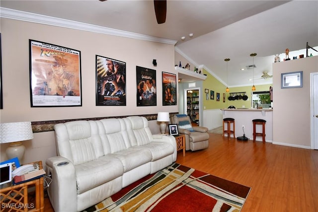 living room with lofted ceiling, wood finished floors, a ceiling fan, and crown molding
