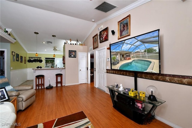 living room featuring visible vents, vaulted ceiling, ornamental molding, wood finished floors, and a ceiling fan