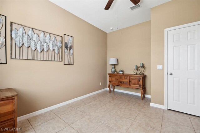 interior space featuring light tile patterned floors, baseboards, visible vents, and ceiling fan