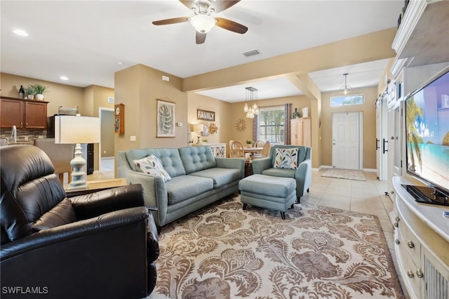 living area featuring light tile patterned floors, visible vents, baseboards, recessed lighting, and ceiling fan with notable chandelier