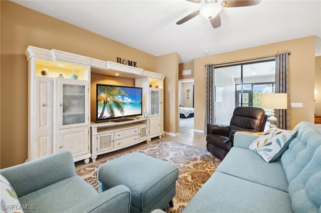 tiled living area with baseboards and ceiling fan