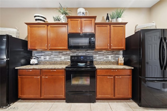 kitchen with light stone countertops, tasteful backsplash, black appliances, and brown cabinetry