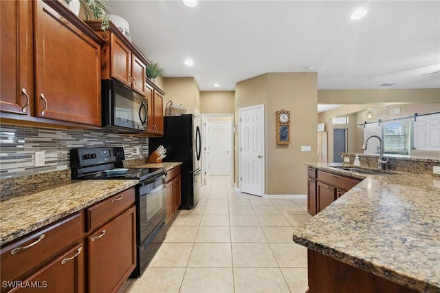 kitchen with tasteful backsplash, light stone countertops, light tile patterned floors, black appliances, and a sink