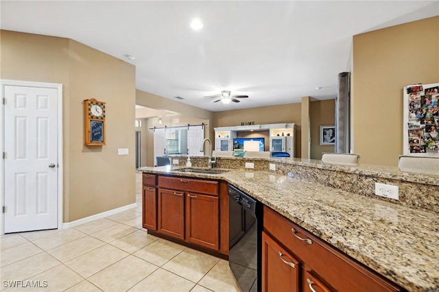 kitchen with a sink, black dishwasher, open floor plan, light tile patterned floors, and light stone countertops