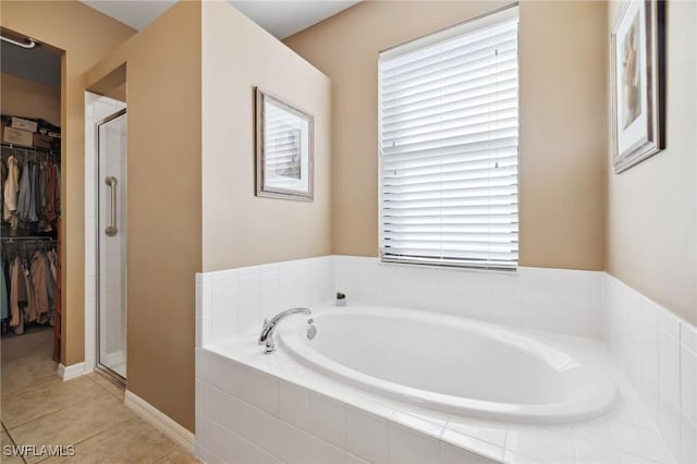 full bath featuring plenty of natural light, a shower stall, a spacious closet, a garden tub, and tile patterned floors