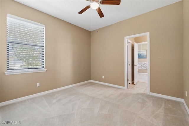 empty room featuring baseboards, light colored carpet, and ceiling fan