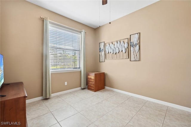 unfurnished room featuring light tile patterned floors, a ceiling fan, and baseboards