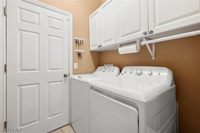 laundry room featuring cabinet space, light tile patterned floors, and washing machine and dryer