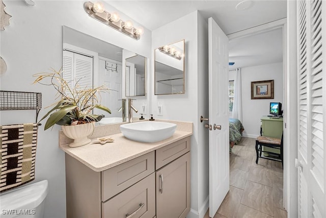 bathroom featuring baseboards, connected bathroom, vanity, and toilet