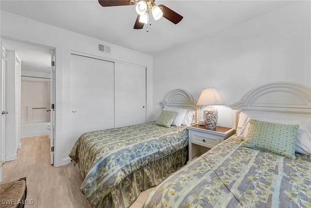 bedroom with wood finished floors, visible vents, a closet, and ceiling fan