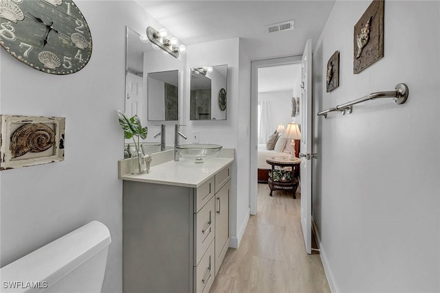 bathroom with visible vents, toilet, vanity, and wood finished floors