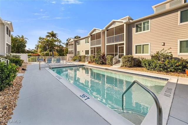 community pool with a patio area and fence