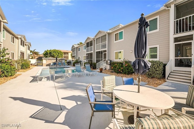 community pool featuring a patio area, outdoor dining space, and a residential view