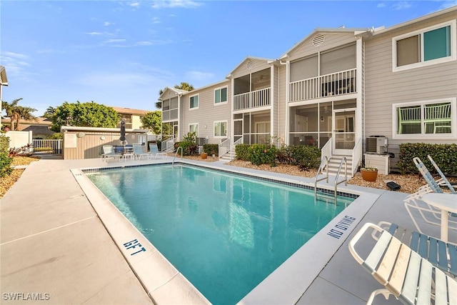 pool with a patio area, central air condition unit, and fence