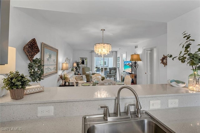 kitchen featuring visible vents, open floor plan, hanging light fixtures, a notable chandelier, and a sink