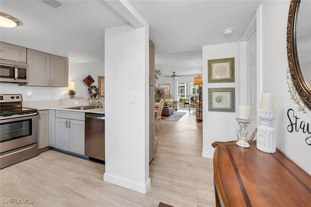 kitchen featuring visible vents, gray cabinets, appliances with stainless steel finishes, and light countertops