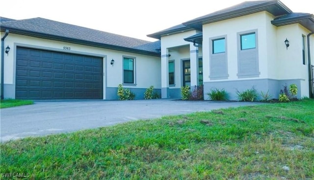 prairie-style home featuring concrete driveway, an attached garage, and stucco siding