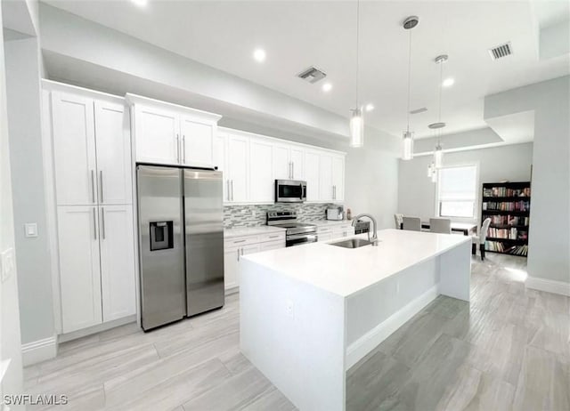 kitchen featuring a sink, visible vents, appliances with stainless steel finishes, and an island with sink