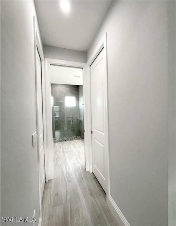 hallway featuring light wood-style flooring and baseboards