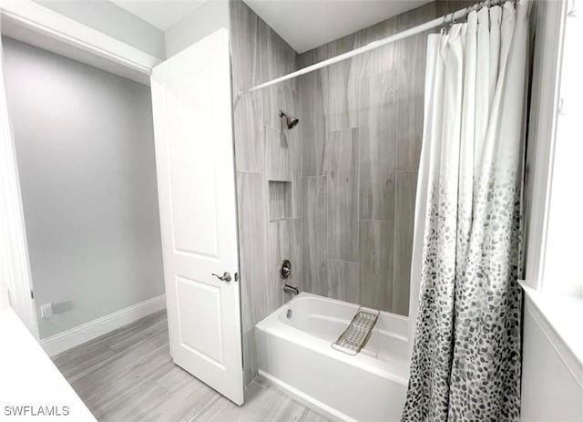 bathroom featuring shower / bath combination with curtain, wood finished floors, and baseboards