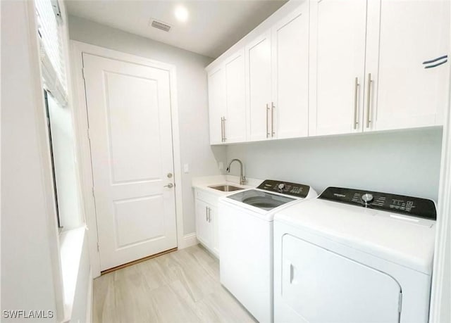 laundry room featuring visible vents, light wood-style floors, cabinet space, independent washer and dryer, and a sink